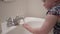 Mother helping baby toddler girl wash her hands with soap in bathroom