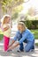 Mother Helping Daughter Tie Shoe Laces On Walk To School