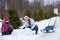 Mother helping her daughter to make a snowman in winter street