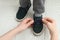 Mother helping son to tie shoe laces at home, closeup