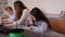 A mother helps her daughter create a model boat with a 3 d pen at a school.