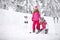 Mother helps her daughter to properly puts ski shoes on skis