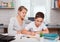 Mother helps son to do lessons. The tutor is engaged with the child