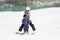 Mother Helps Toddler Boy Ski Downhill. Dressed Safely with Helmet