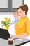 Mother with her baby in her hands working at the laptop, near a vase full with tulips, and drinking coffee