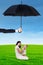 Mother and her baby playing under umbrella at field