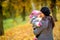 Mother with her beloved toddler walks in the autumn park, holds on her hands and gently hugs