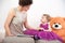 Mother and her curious daughter in violet dress with teddy bear