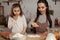 Mother and her daughter are baking a bread and having fun at the kitchen.