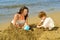 Mother and her daughter playing with toys and sand at beach