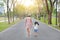 Mother and her daughter walking on the road and holding hands in the outdoor nature garden. Back view