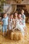 mother and her four children, standing in front of wooden doors leading to barn, are feeding a white baby goat