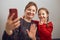 Mother with her little daughter making video call using mobile phone. Woman and little girl talking with relatives. Cheerful