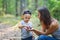 Mother and her little son discovering nature looking on pine-tree cones