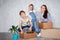 A mother with her son and daughter moves into a new apartment with things in cardboard boxes. The family creates a roof