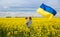 Mother with her son and large satin flag of Ukraine among a blooming yellow rapeseed field. Glory to Ukraine