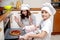 Mother and her son in white chef hats preparing a cake in the kitchen.