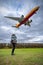 Mother with her toddler, admiring a large airplane soaring across the bright blue sky