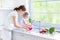 Mother and her toddler daughter washing vegetables