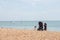 A mother and her young daughter sitting on the pebbles in a british beach enjoying the sun at the seaside