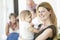 Mother Holding Baby On Porch With Family Behind