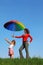 Mother holding colorful umbrella over her daughter