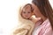 Mother holding cute little baby wrapped with hooded towel after bath on light background, closeup