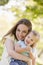 Mother holding daughter outdoors smiling