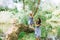 mother holding hands with daughter and helping her to walk on tree trunk with lake