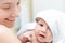 Mother holding infant baby after bathing. Cute child in white towel on moms hand after having bath. Children care and hygiene con