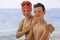 Mother holding shoulders of teenage son, two Caucasian people standing on coastline, looking at camera