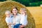 Mother holding two children on arms on wheat field in summer