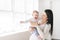 Mother holds baby on a beautiful room with white window