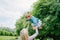 Mother holds on her hands, throws up lifts on her hands up daughter in the summer in the park. Mom and child in nature