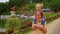 Mother Holds Little Girl on Shoulders Walks along Lake Smiles