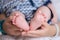 Mother holds newborn baby`s bare heels. Tiny feet in woman`s hand. Cozy morning at home.