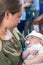 Mother holds sleeping new born baby boy during baptism ceremony.