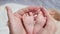 Mother holds tiny pink feet of newborn daughter on bed