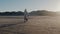 Mother hugging little running daughter at amazing sunny windy winter sea beach, two cars in the background slow motion.