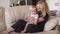 Mother hugs and kisses her adorable baby on sofa