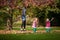 Mother and identical twins having fun with autumn leaves in the park, blond cute curly girls, happy kids, girls in pink jacket