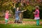 Mother and identical twins having fun with autumn leaves in the park, blond cute curly girls, happy kids, girls in pink jacket