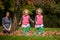 Mother and identical twins having fun in autumn in the park, blond cute curly girls, happy family, beautiful girls in pink jackets