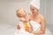 Mother and infant baby boy in white towels after bathing apply sunscreen or after sun lotion. Children skin care in a hotel or