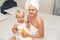 Mother and infant baby in white towels after bathing apply sunscreen or after sun lotion or cream. Children skin care. Spf, skin