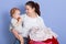 Mother with infant son sitting near laundry basin, mummy looking at her baby with love, cheeper wearing stripped bodysuit nibbles