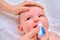 Mother instills nasal drops in Infant baby, face close-up