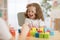 Mother and kid daughter playing colorful block toys at home