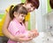 Mother and kid daughter washing their hands in the bathroom. Care and concern for children.