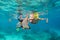 Mother, kid in snorkeling mask dive underwater with tropical fishes